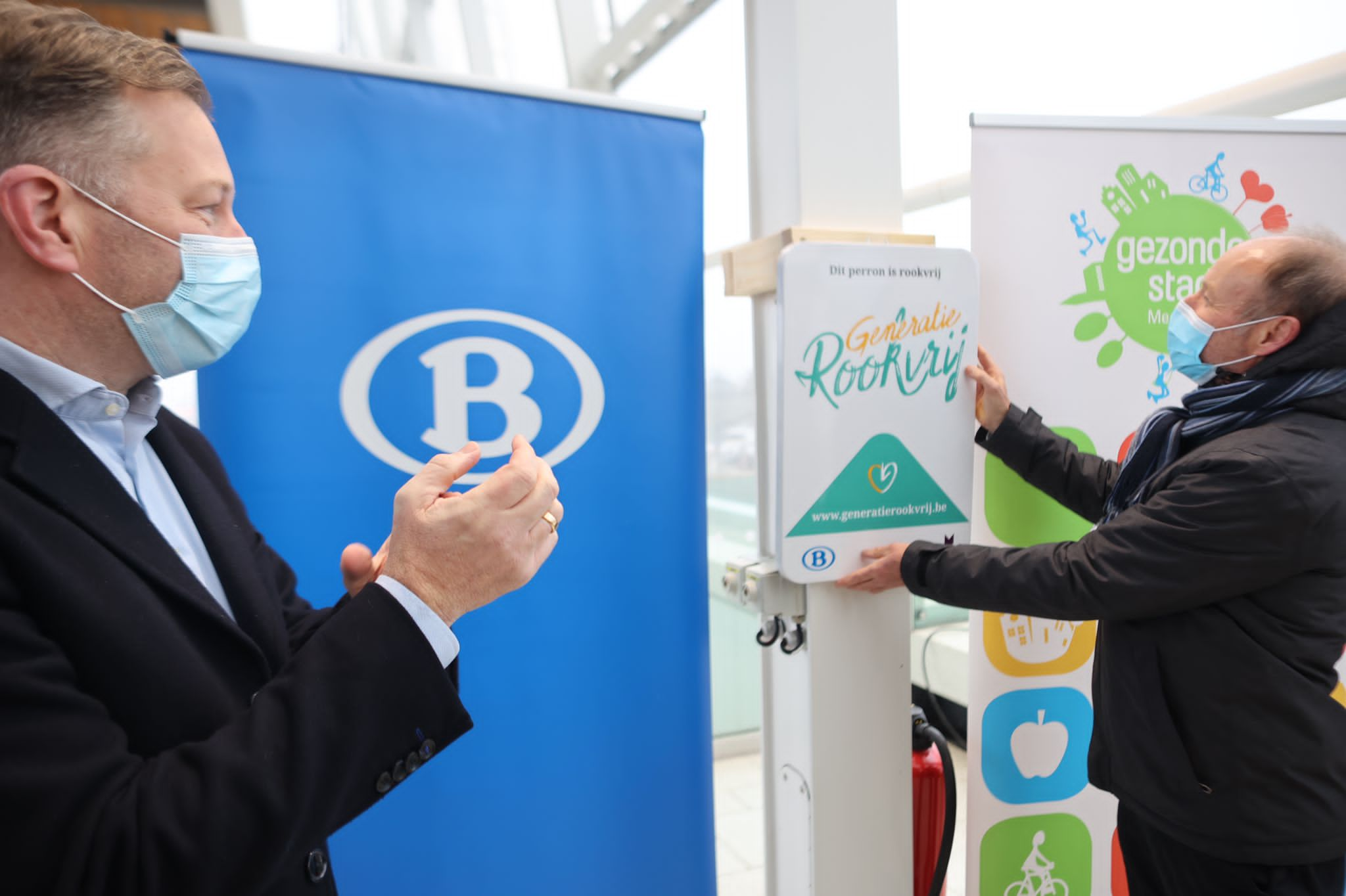 Hedwig Verhaegen, directeur Kennis en Beleid bij Kom op tegen Kanker, hangt het bord op en maakt zo het perron rookvrij. © NMBS